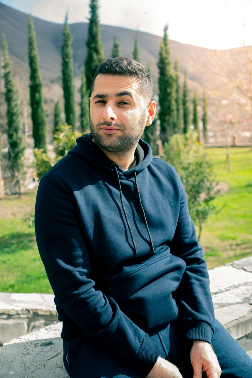 a man sitting on a ledge in a park