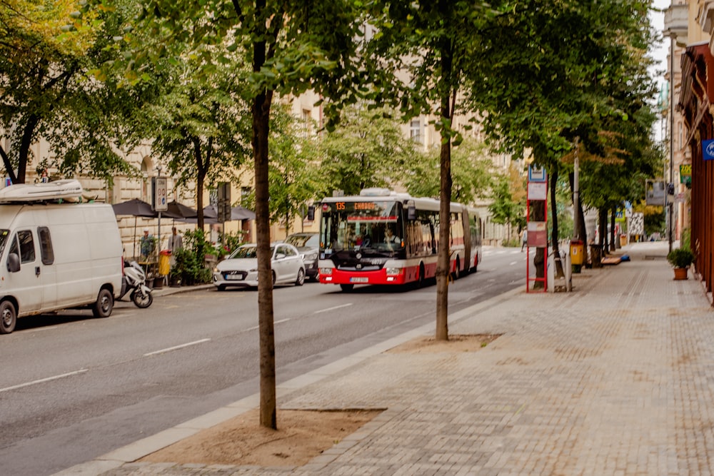 a red and white bus driving down a street next to tall buildings