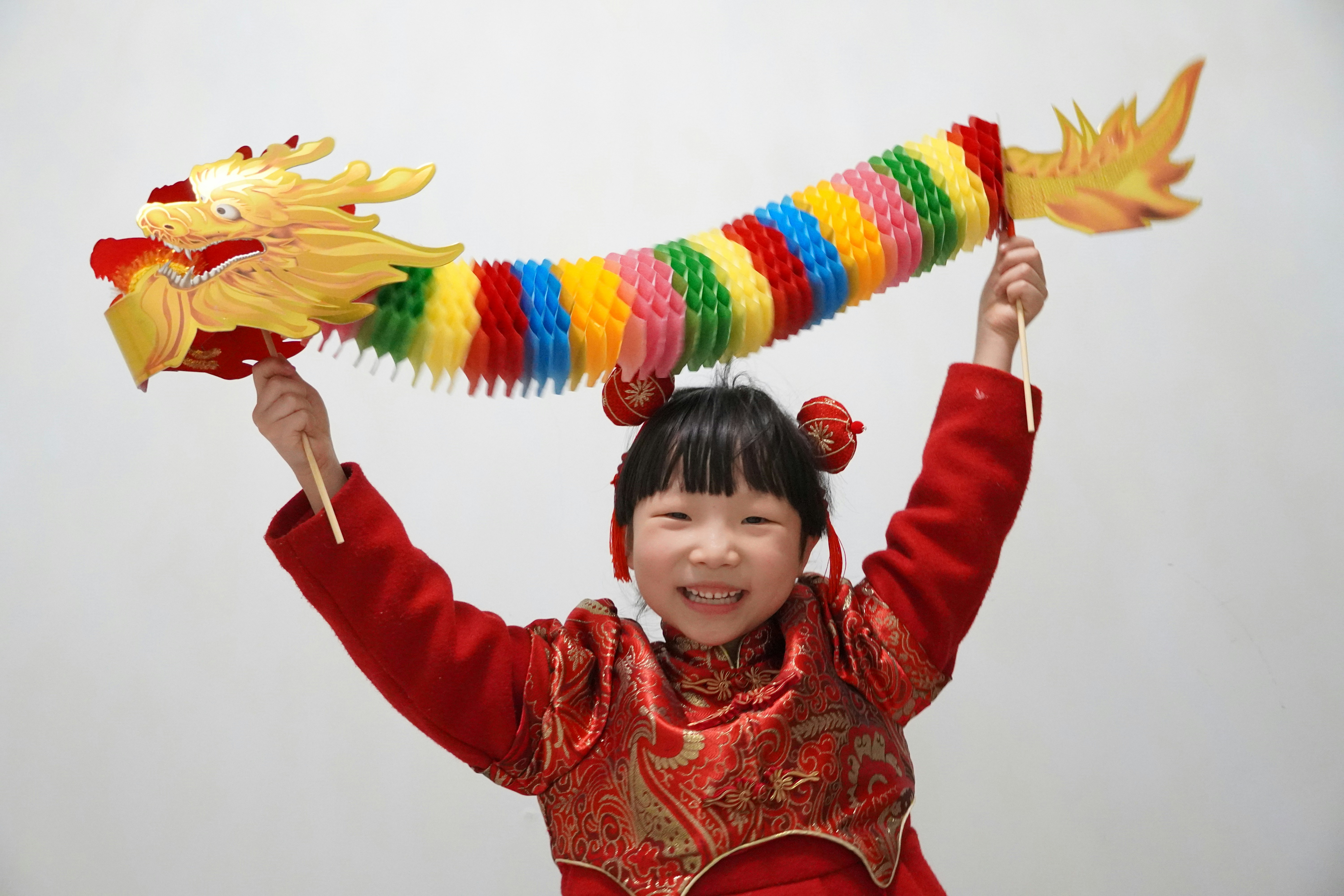 a young girl in a red dress holding a dragon kite
