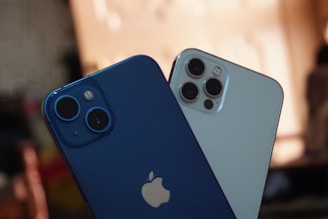 two blue and white iphones sitting next to each other