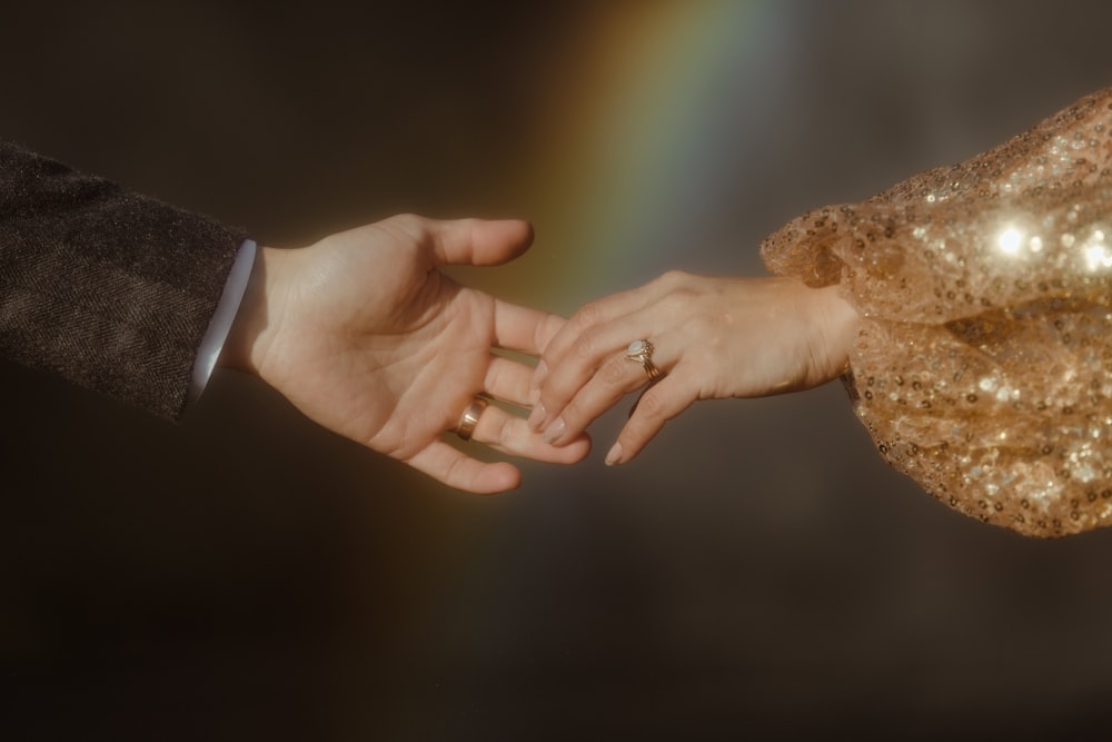 a man and a woman holding hands with a rainbow in the background