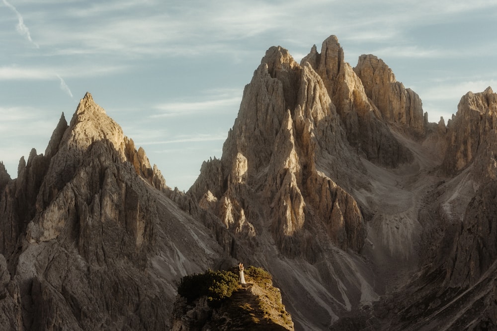 uma pessoa em pé sobre um afloramento rochoso nas montanhas