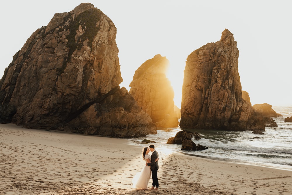 a bride and groom standing on the beach