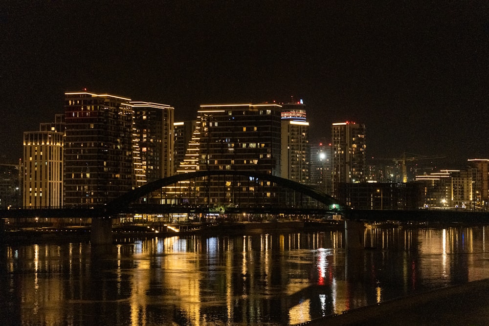 Una ciudad de noche con un puente sobre el agua