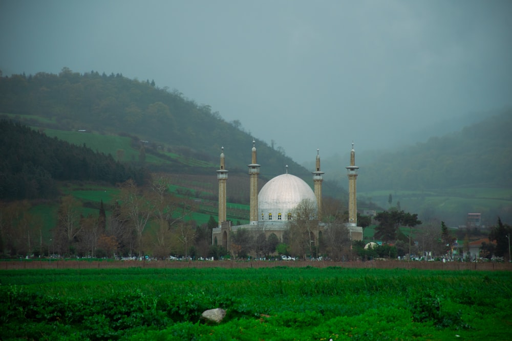 a large white building sitting on top of a lush green field