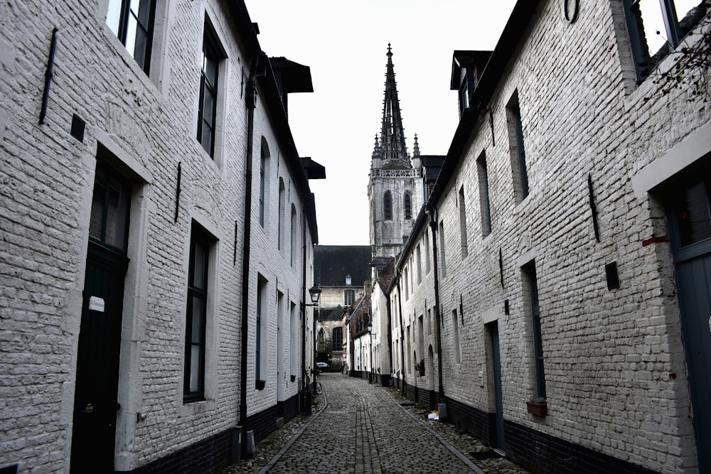 a cobblestone street with a church steeple in the background