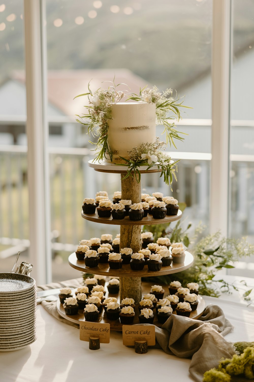 a cake and cupcakes on a table in front of a window