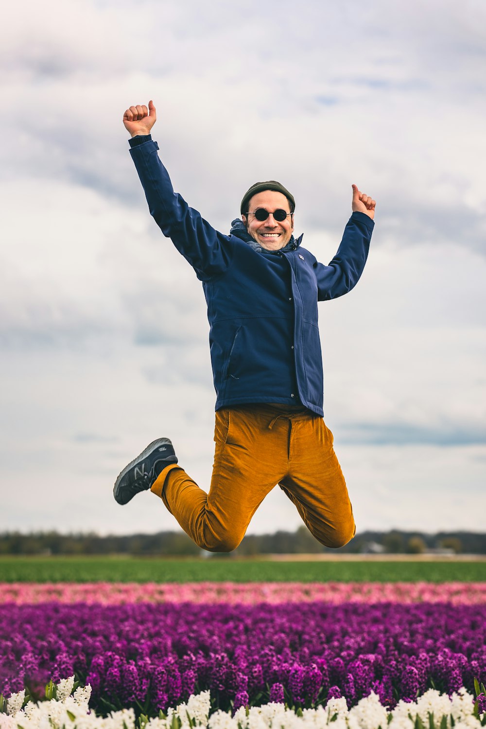 a man jumping in the air in a field of flowers