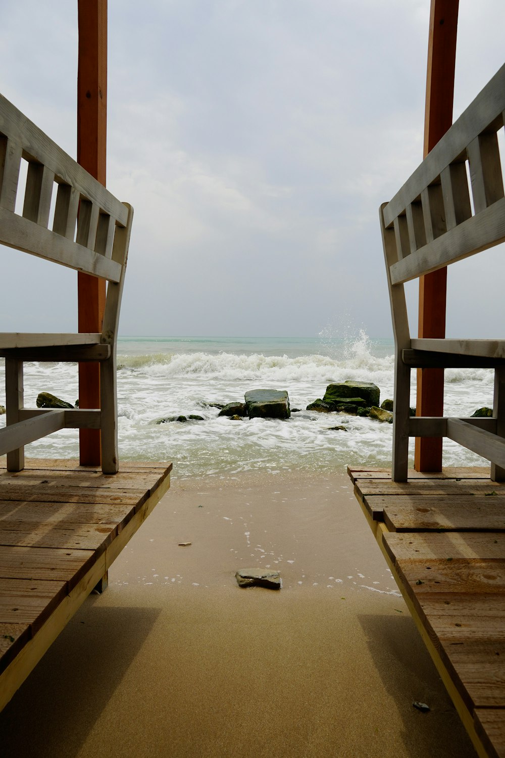 a couple of benches sitting on top of a sandy beach