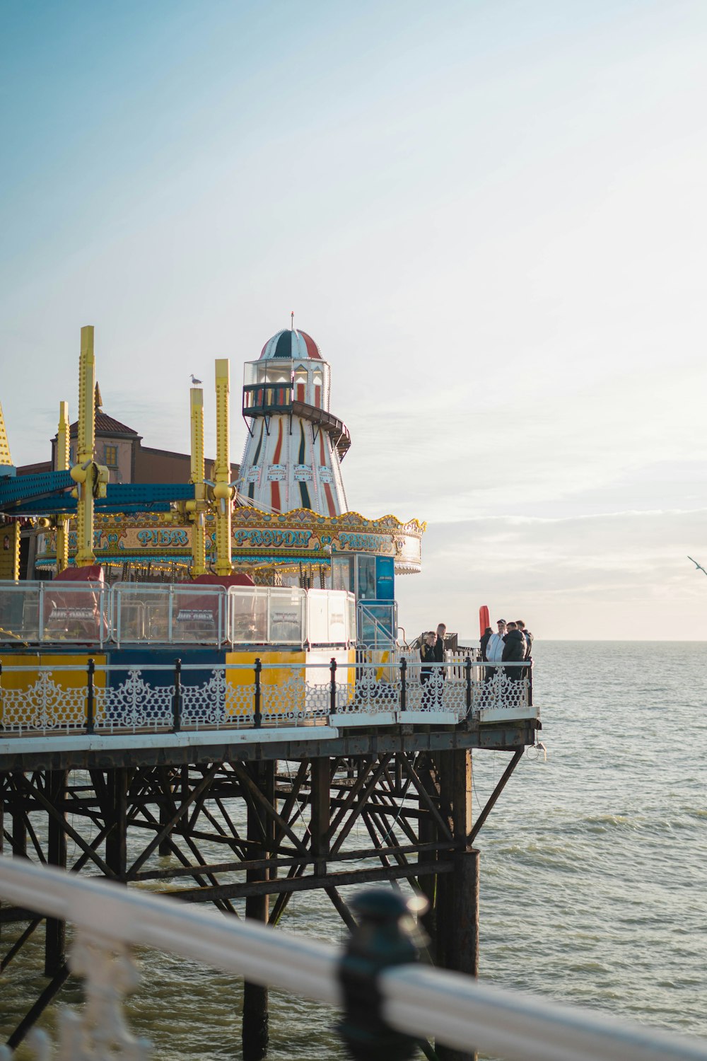 a ferris wheel sitting on top of a pier next to the ocean