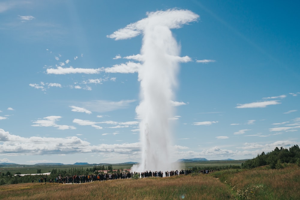 a group of people standing in front of a geyser