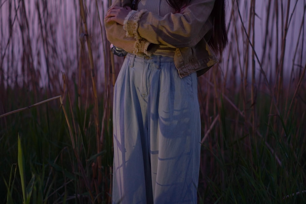 a woman standing in a field with her arms crossed