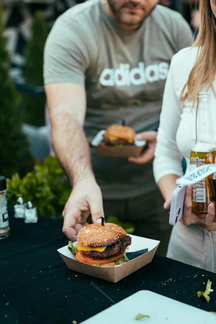 a man and a woman standing over a hamburger