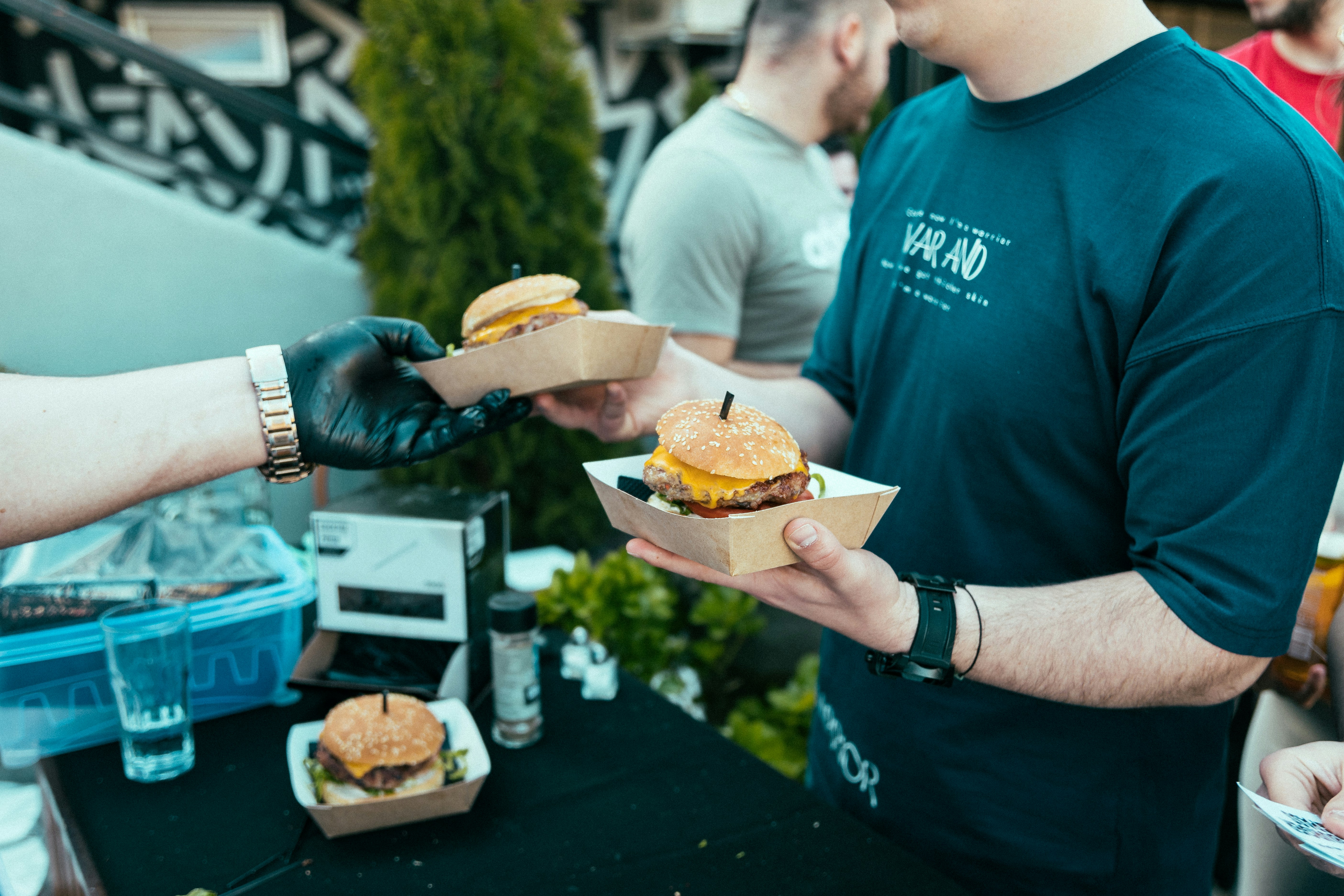 a group of people standing around a table with sandwiches