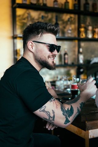 a man sitting at a bar with a tattoo on his arm