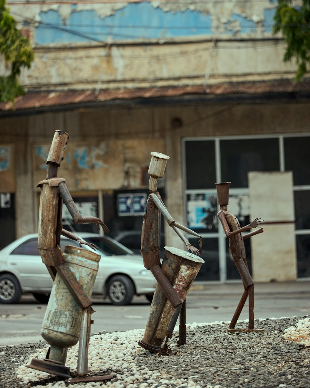 a couple of rusty metal sculptures sitting on top of a street