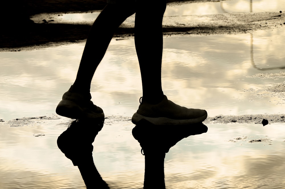 a reflection of a person's legs in a puddle