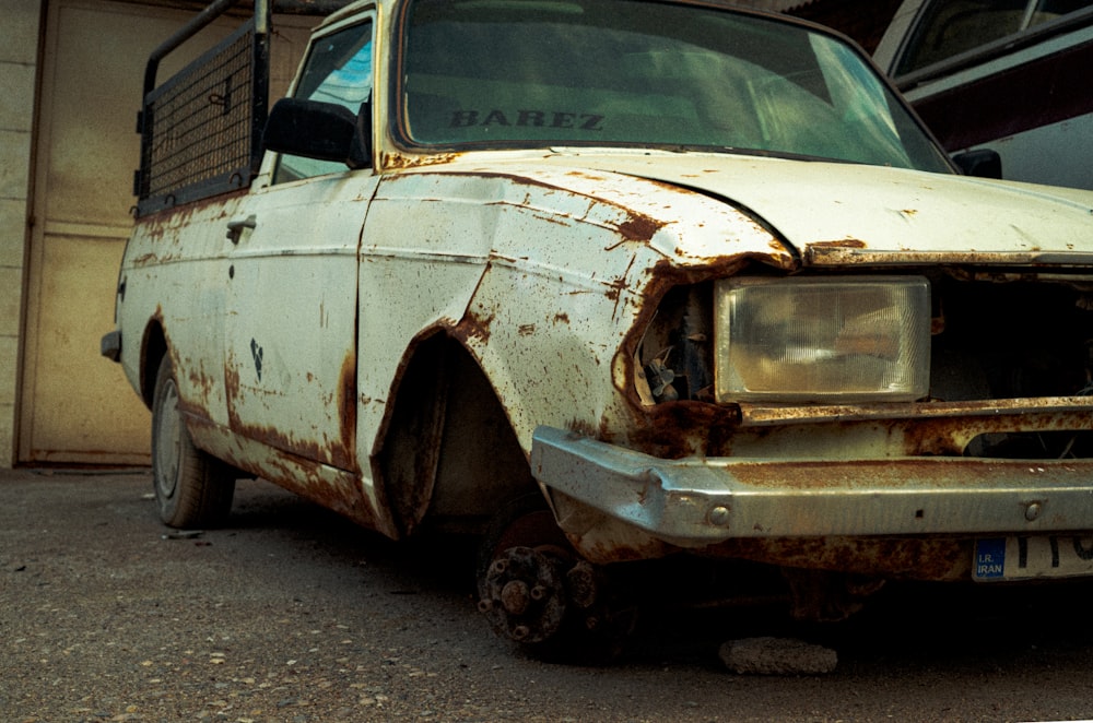 a rusted out car parked in front of a building