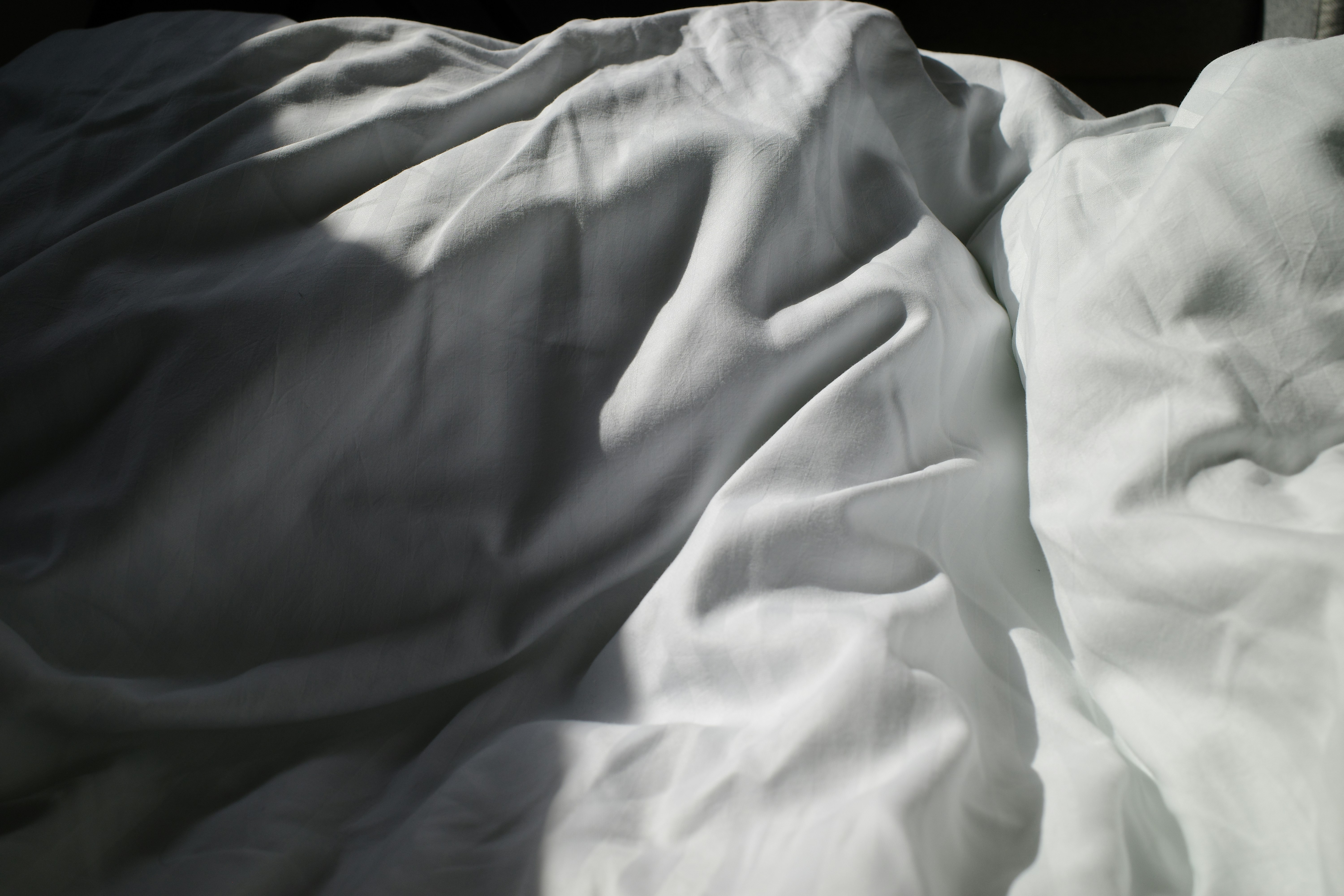 an unmade bed with white sheets and white sheets