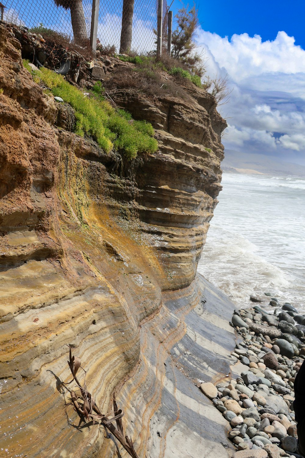 a beach with a cliff and a fence on top of it