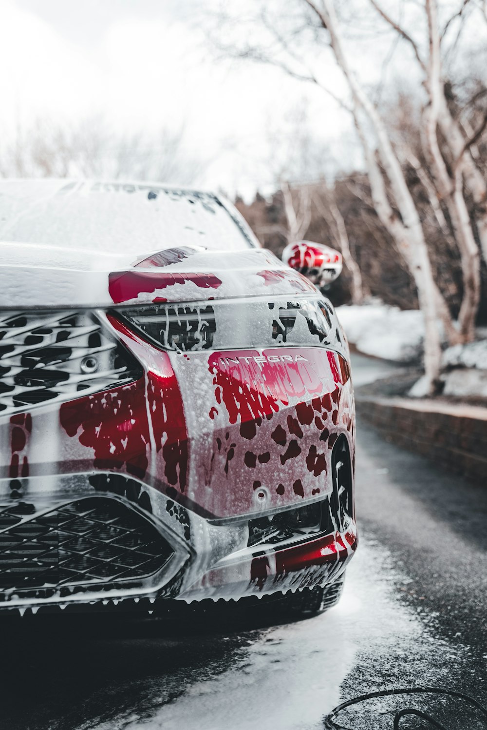 a red car parked on the side of a road covered in snow