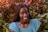 a woman is smiling in front of a bush