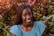 a woman is smiling in front of a bush