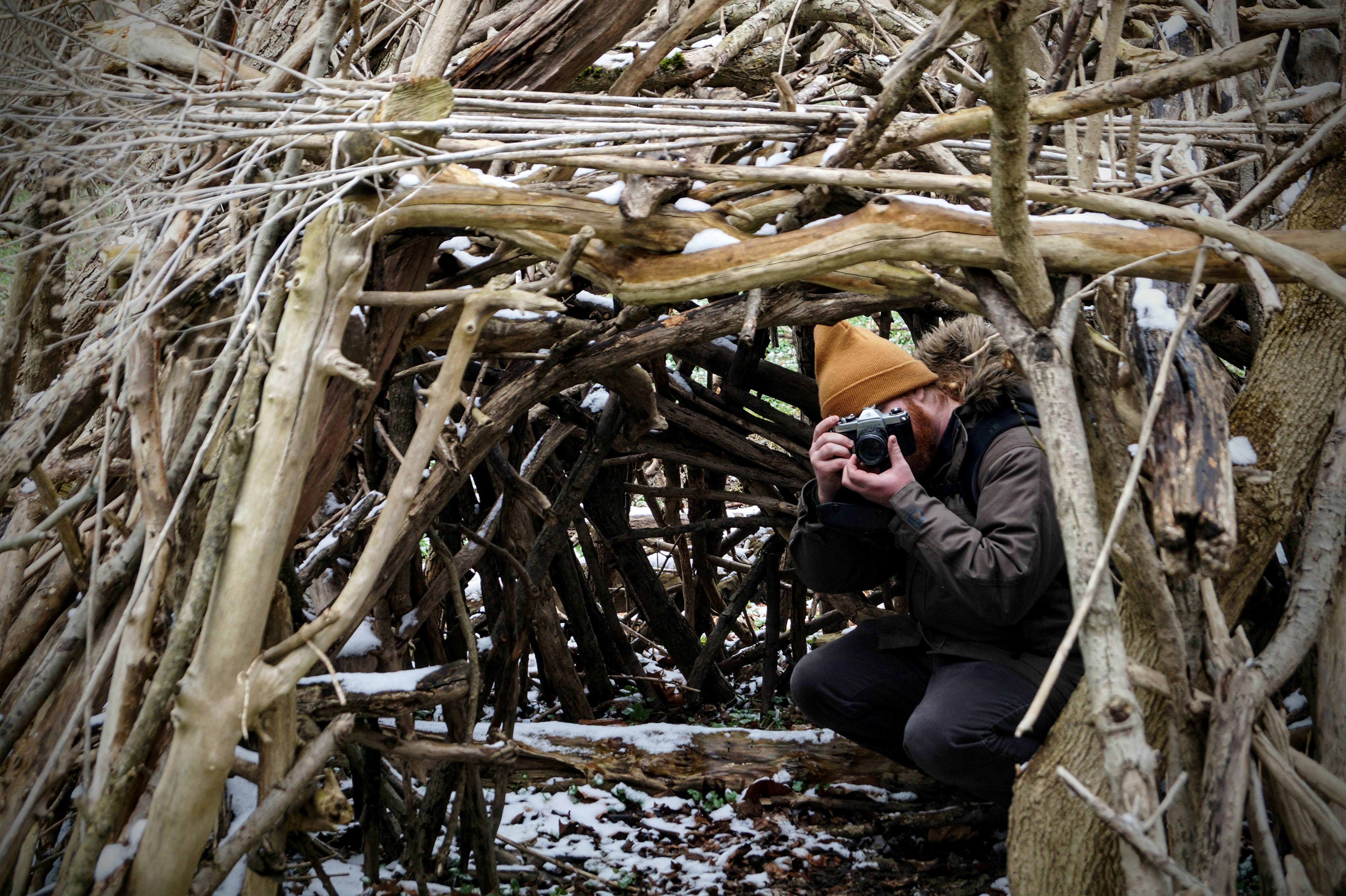 a man taking a picture of a pile of branches