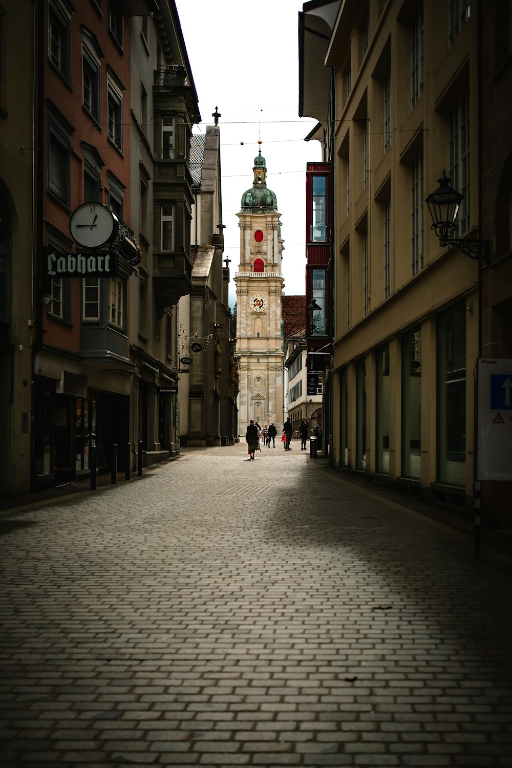 a cobblestone street with a clock tower in the background