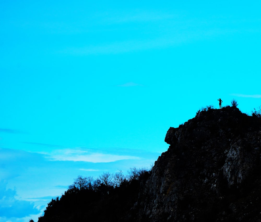 a person standing on top of a mountain with a sky background