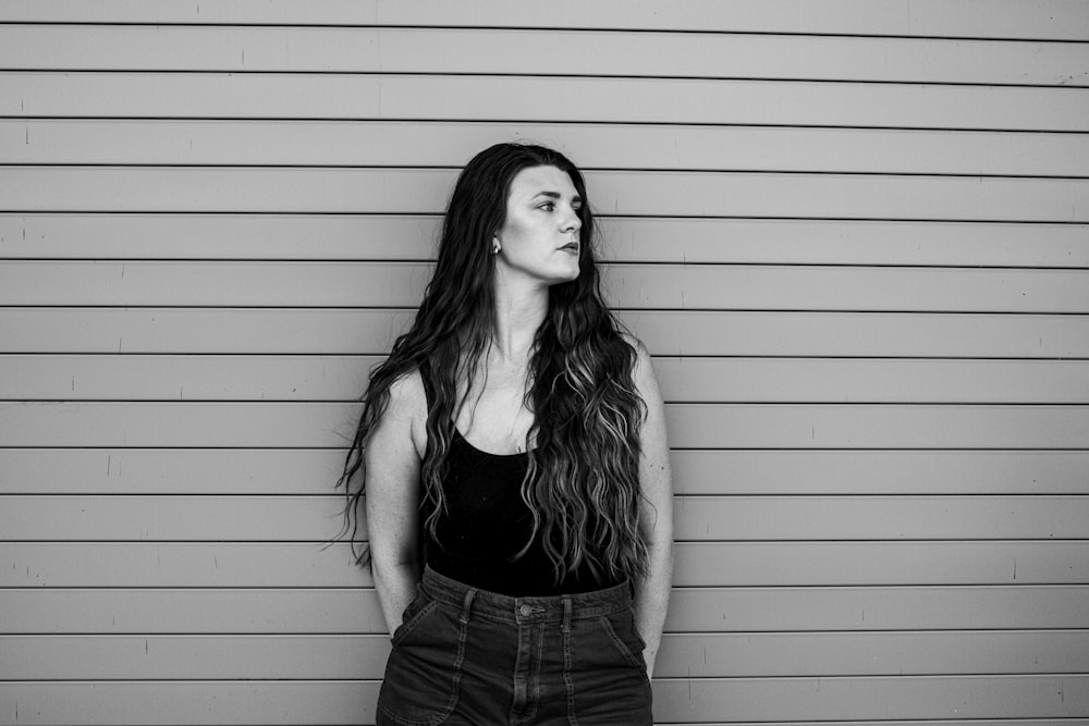 a woman with long hair standing in front of a wall