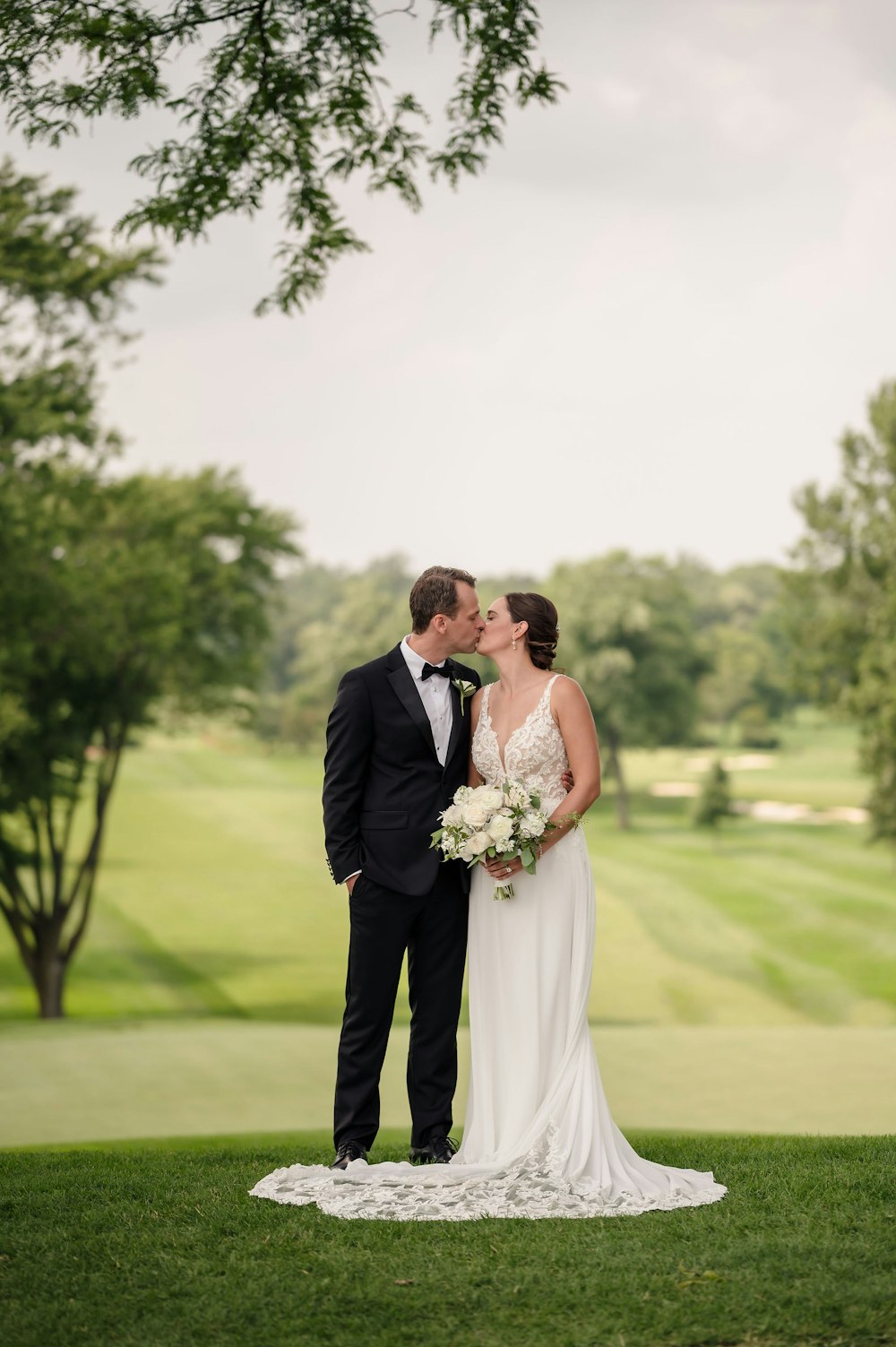 a bride and groom kissing in front of a golf course