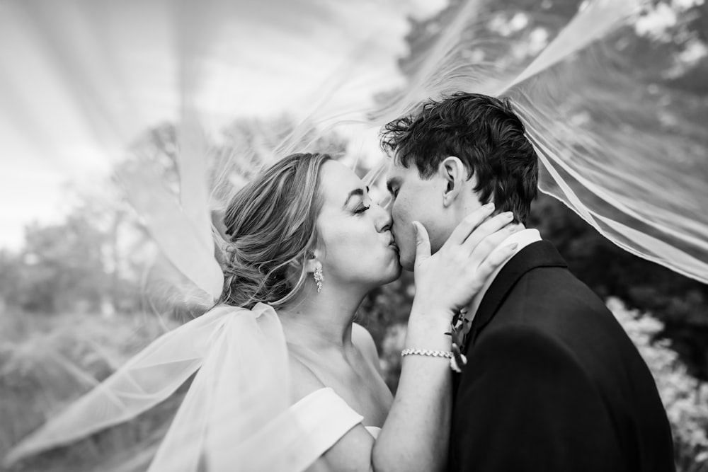a bride and groom kissing under a veil