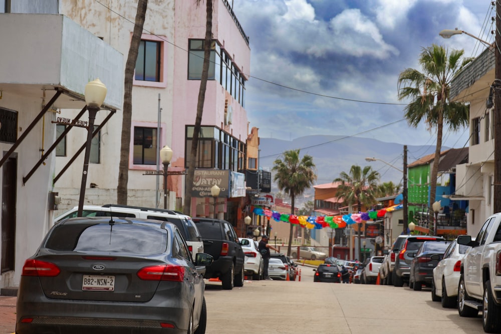 a street filled with lots of parked cars next to tall buildings