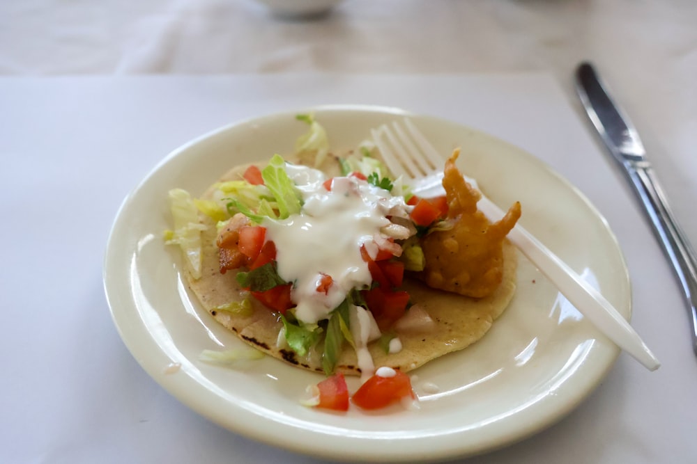 a white plate topped with a taco and a fork