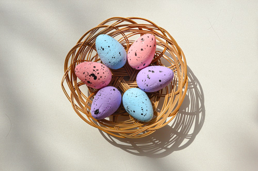 a basket filled with colorful speckled eggs on top of a table