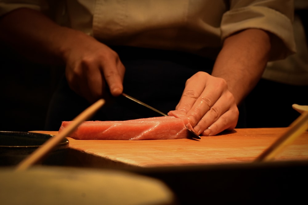 a person cutting up a piece of meat on a cutting board