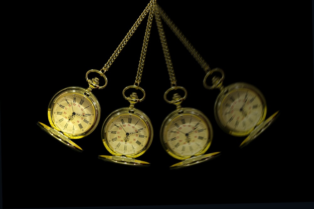 a group of four clocks hanging from chains