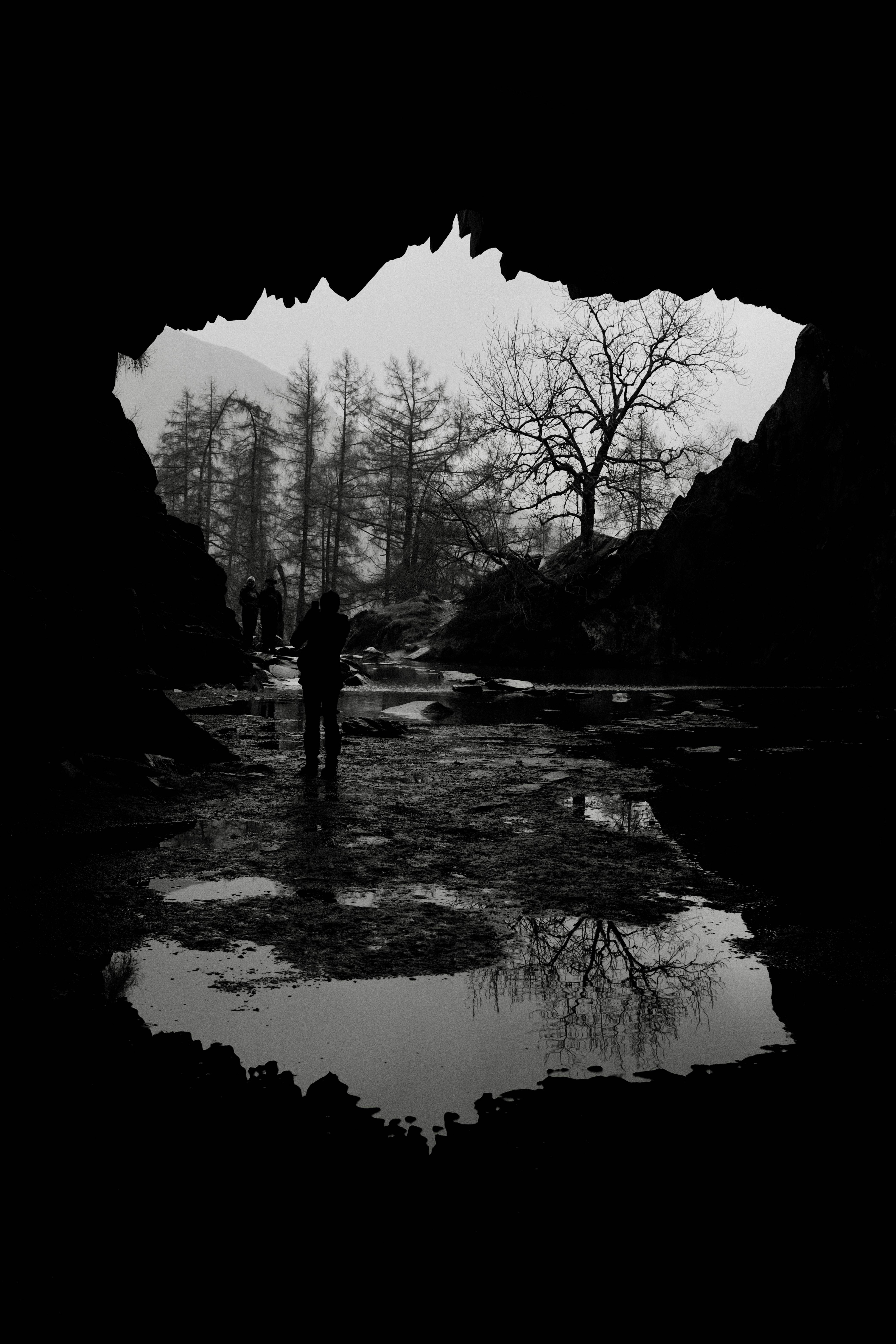 a black and white photo of a person standing in a cave