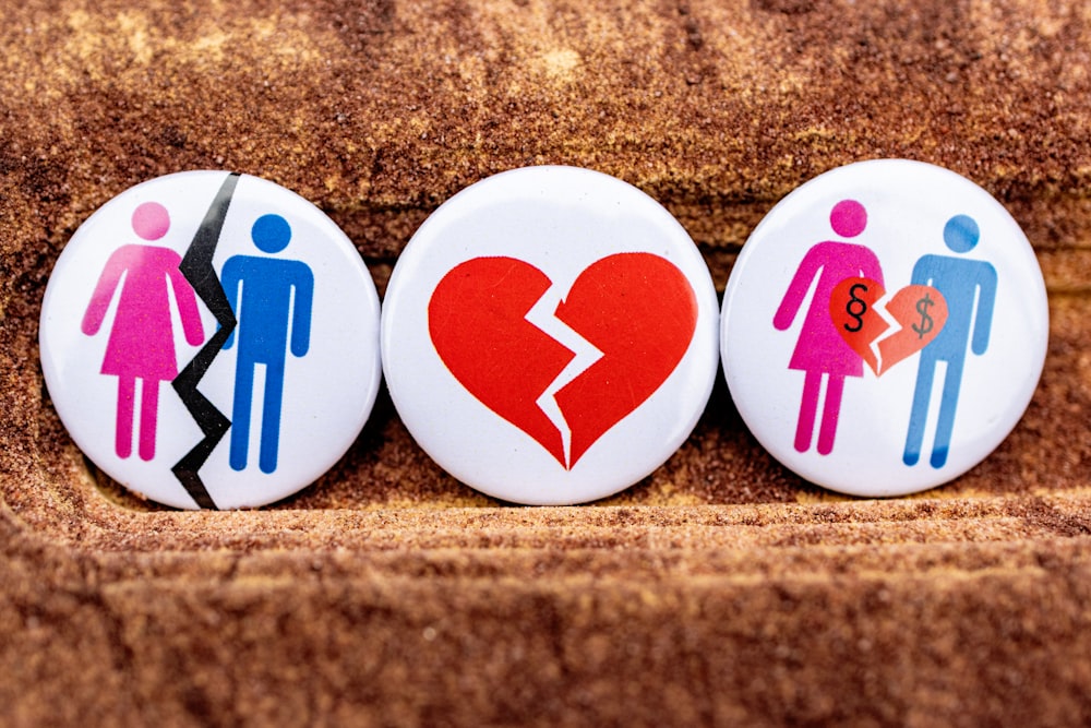 tre bottoni raffiguranti un cuore spezzato, un uomo e una donna