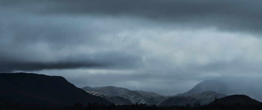 a mountain range under a cloudy sky with mountains in the background