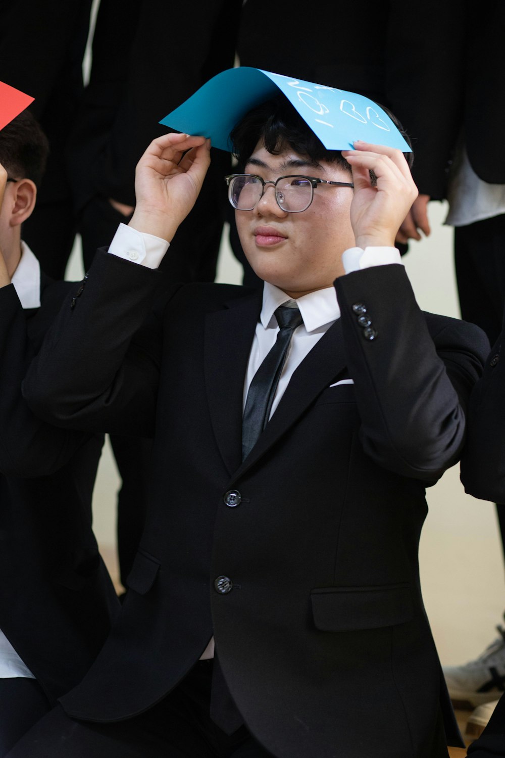 a man in a suit and tie holding a paper hat over his head