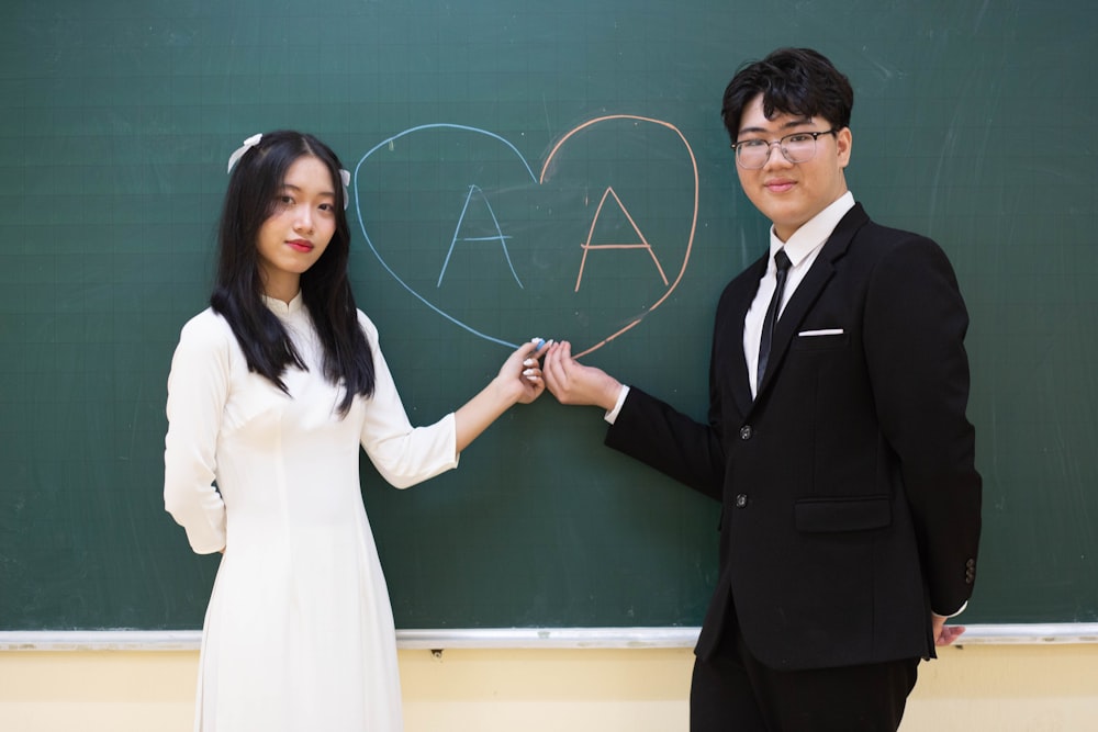 a man and a woman standing in front of a blackboard