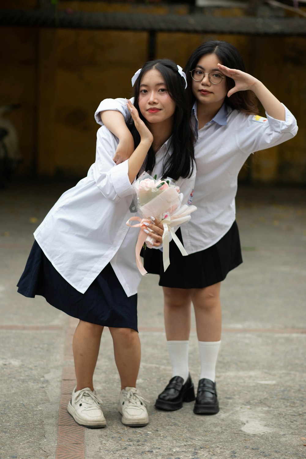 two young girls dressed in school uniforms posing for a picture