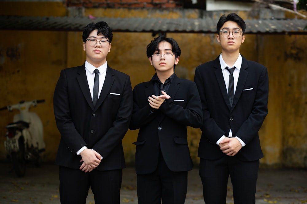 three young men in suits standing next to each other