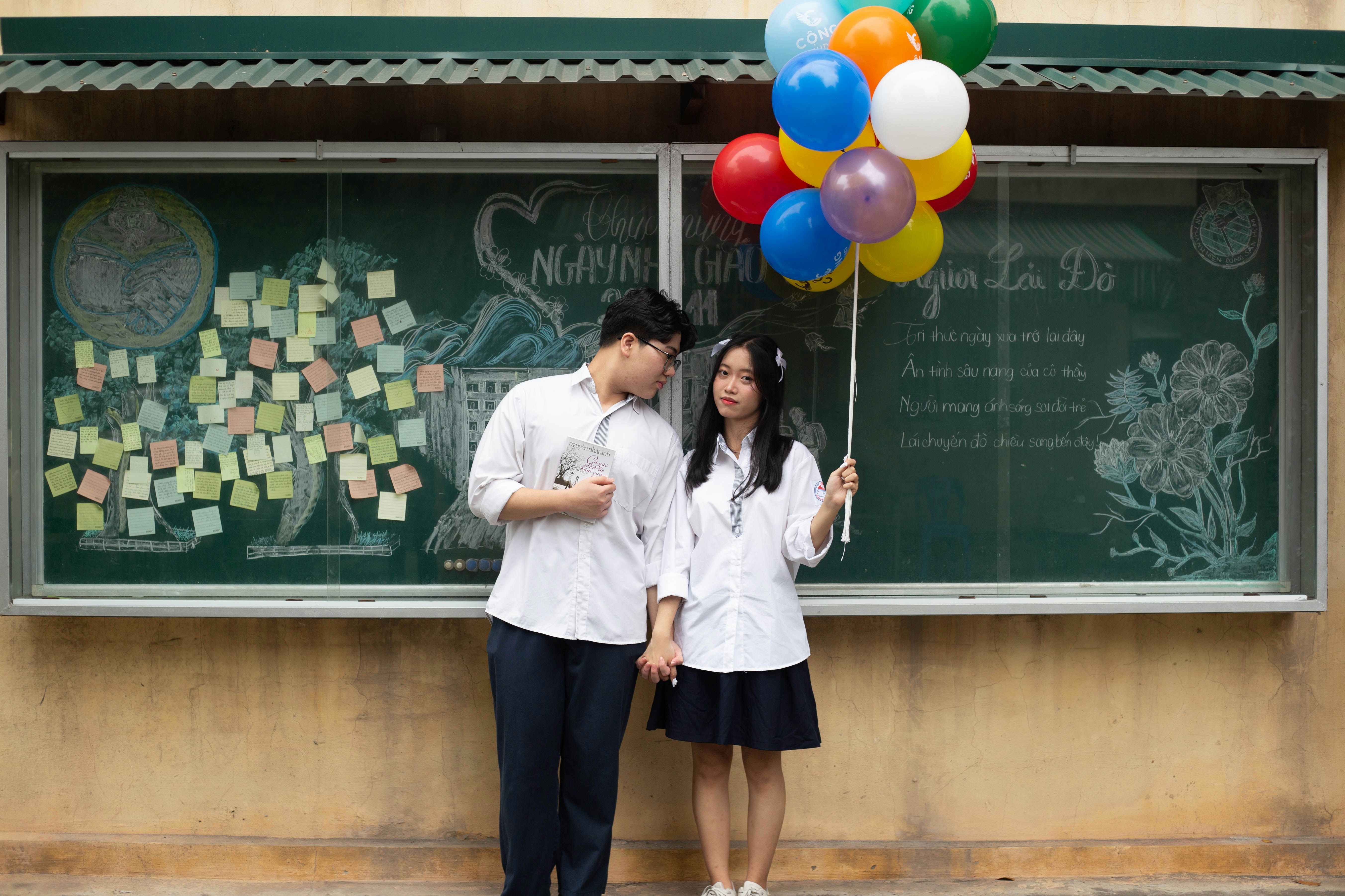 a man and a woman standing in front of a chalkboard with balloons