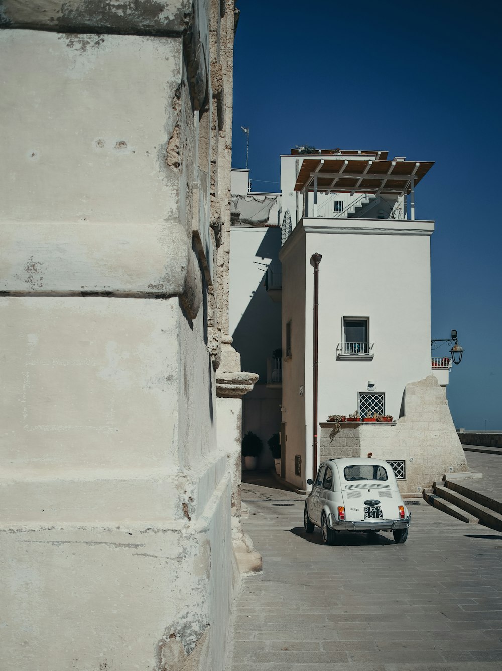 a white car parked in front of a white building