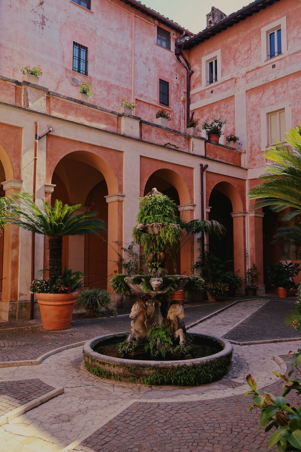 a courtyard with a fountain surrounded by potted plants