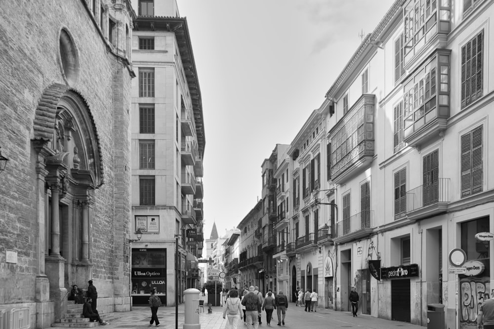 a group of people walking down a street next to tall buildings