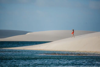 a woman in a red dress standing on top of a sand dune
